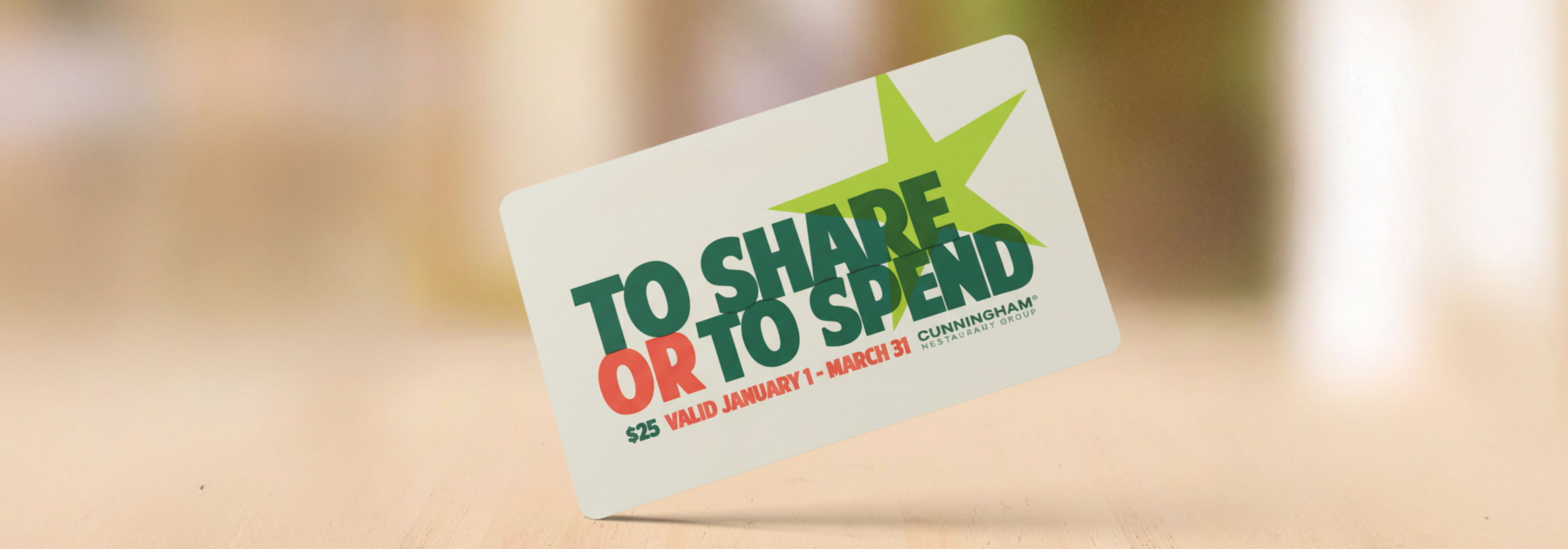 $25 “To Share or To Spend” gift card on a blurred tabletop.