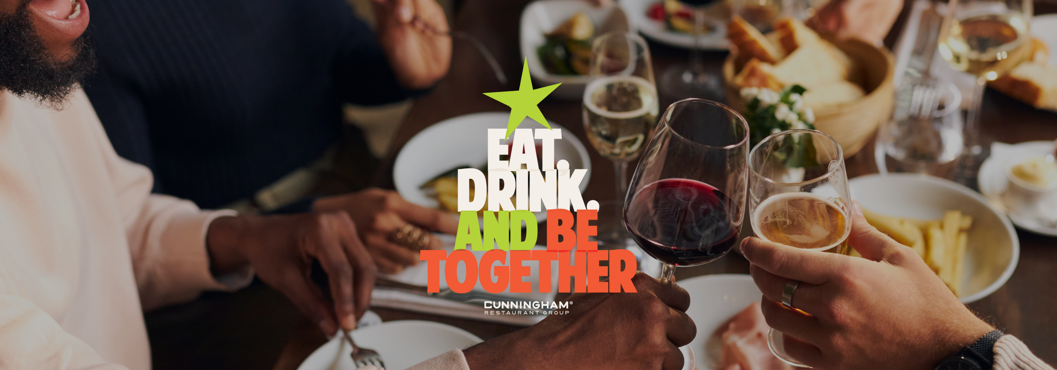 People clinking wine and beer glasses over a dinner table with the text “EAT. DRINK. AND BE TOGETHER” in the center.