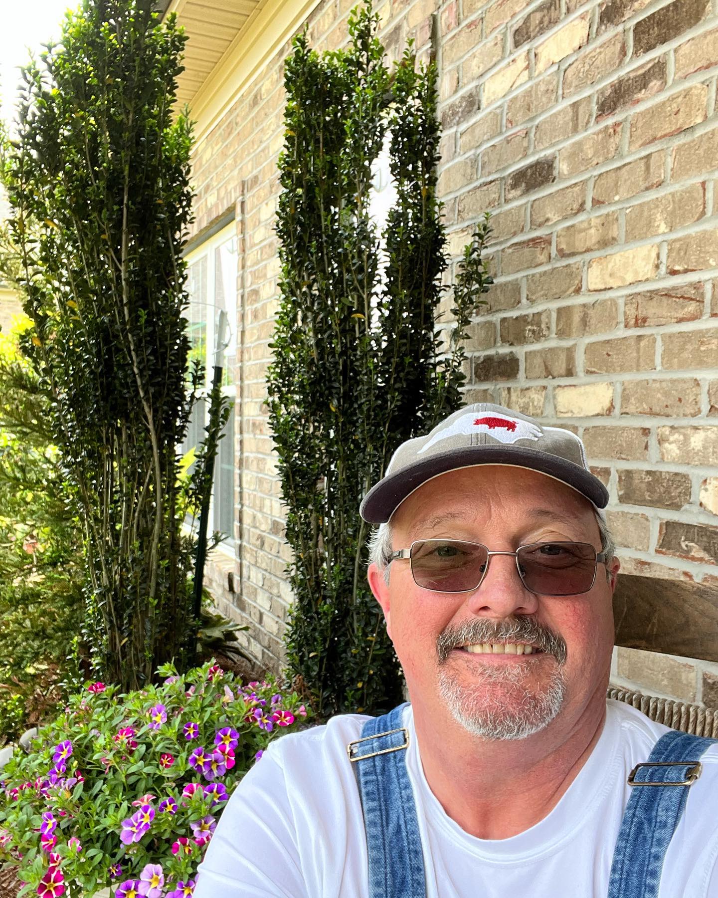 a man wearing a hat and sunglasses standing outside of a building