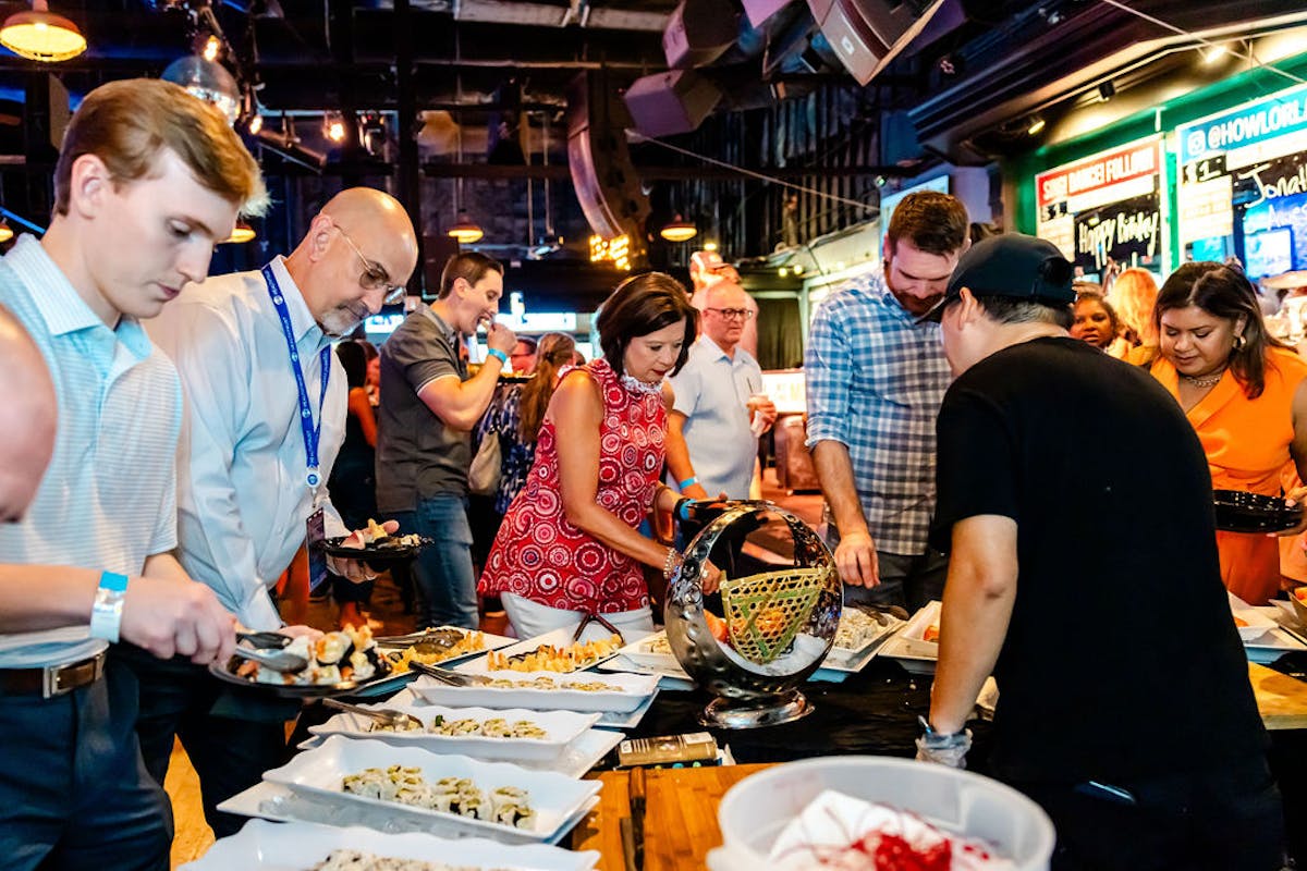 a group of people standing around a table eating cake