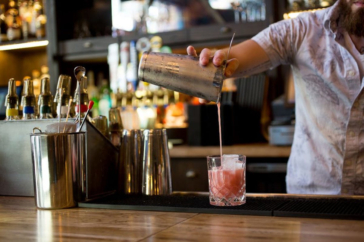 a person holding a glass of beer on a table