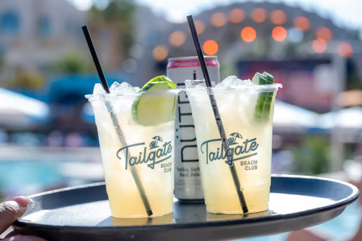 Branded cocktails on server tray, poolside bokeh at Tailgate Beach Club