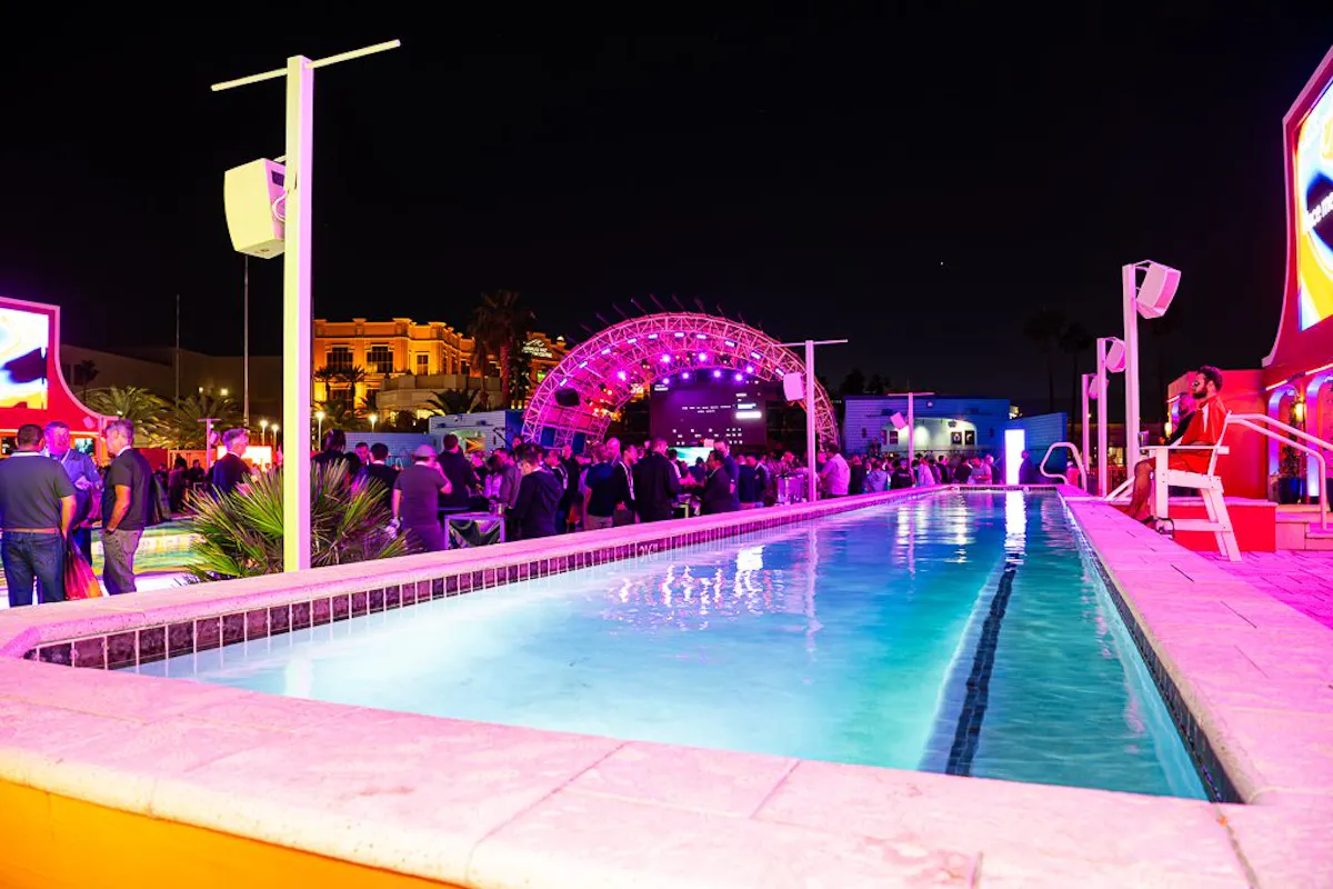 Lap pool glowing at night with the lit stage arch and Mandalay Bay behind