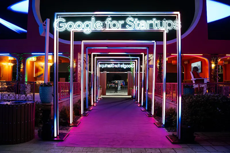 Neon arch tunnel entrance with a magenta carpet leading into the venue
