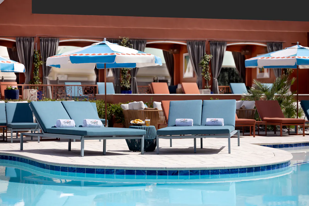 Empty daybeds and umbrellas along pool edge at Tailgate Beach Club