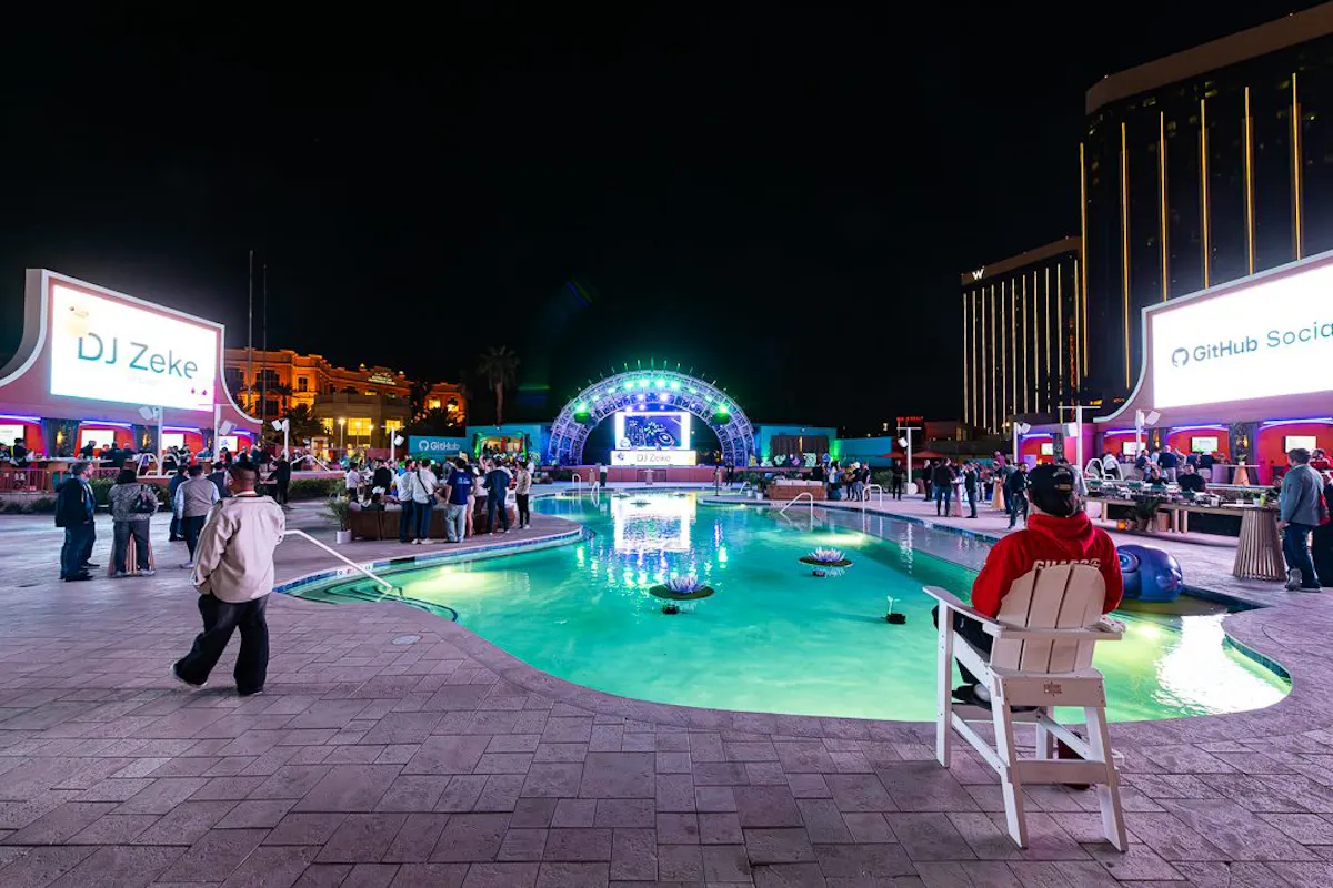 Green-lit pool at night with guests around the deck