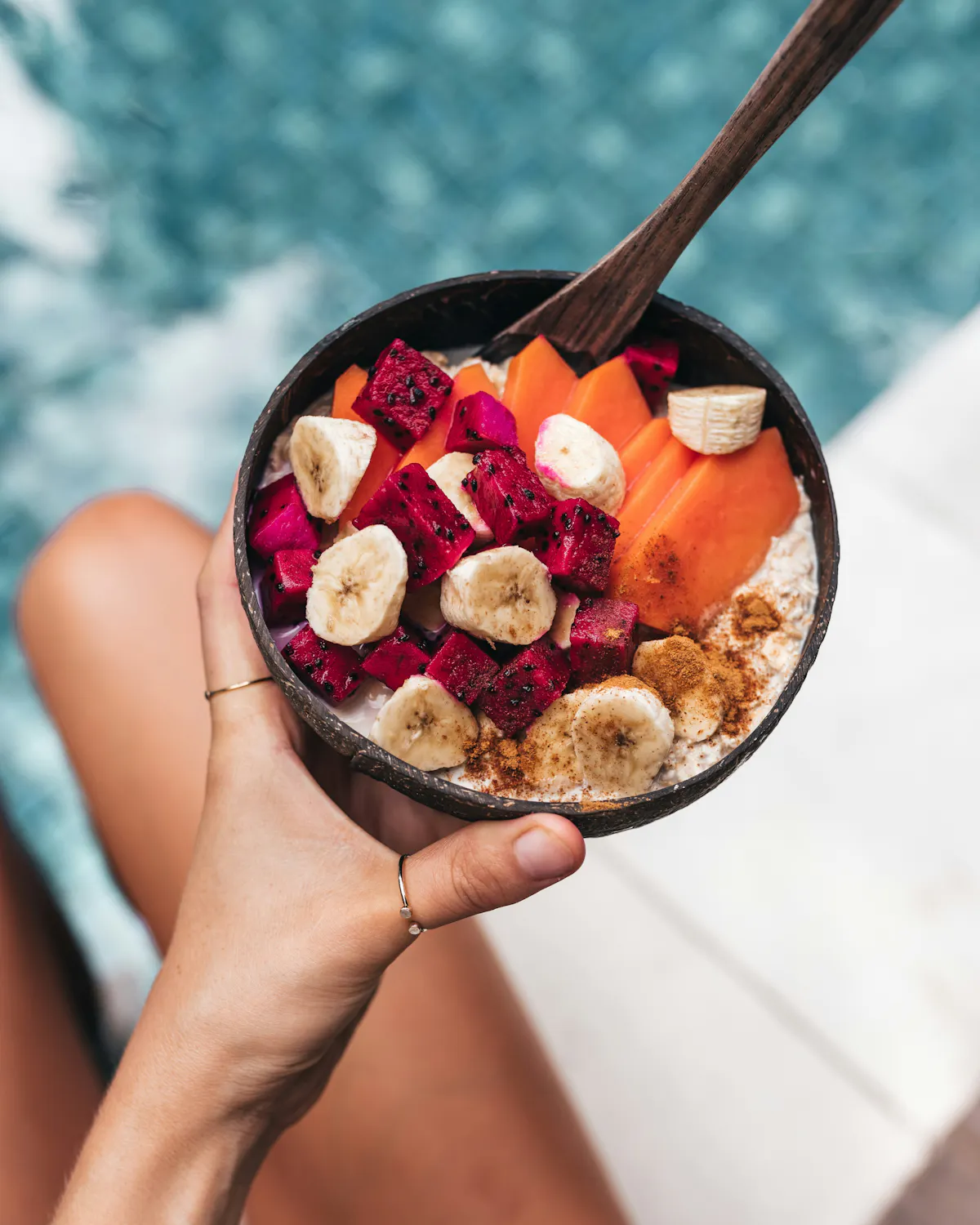 Hand holding fruit acai bowl poolside at Tailgate Beach Club