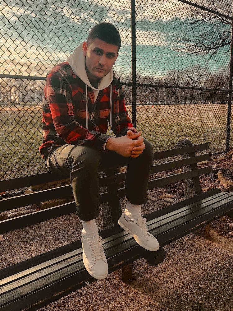 a person sitting on a bench next to a fence