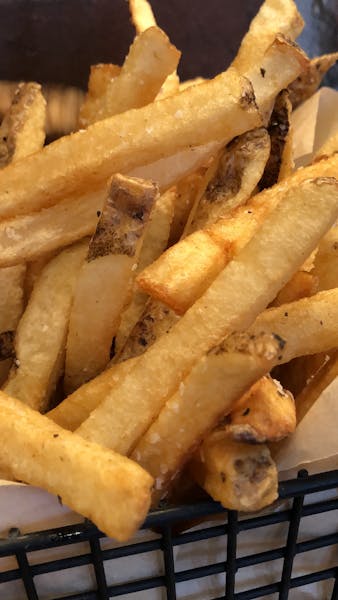 a hot dog on a bun next to some fries