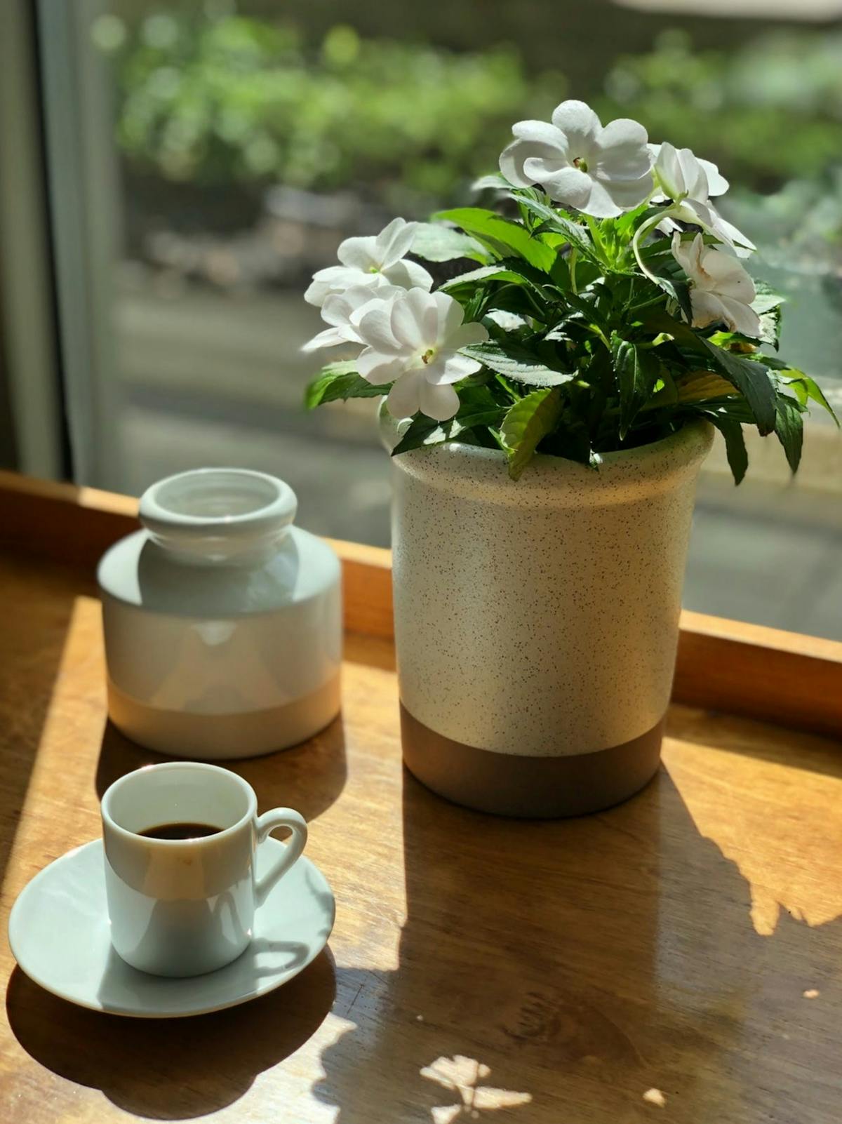 a cup of coffee and a vase of flowers on a table