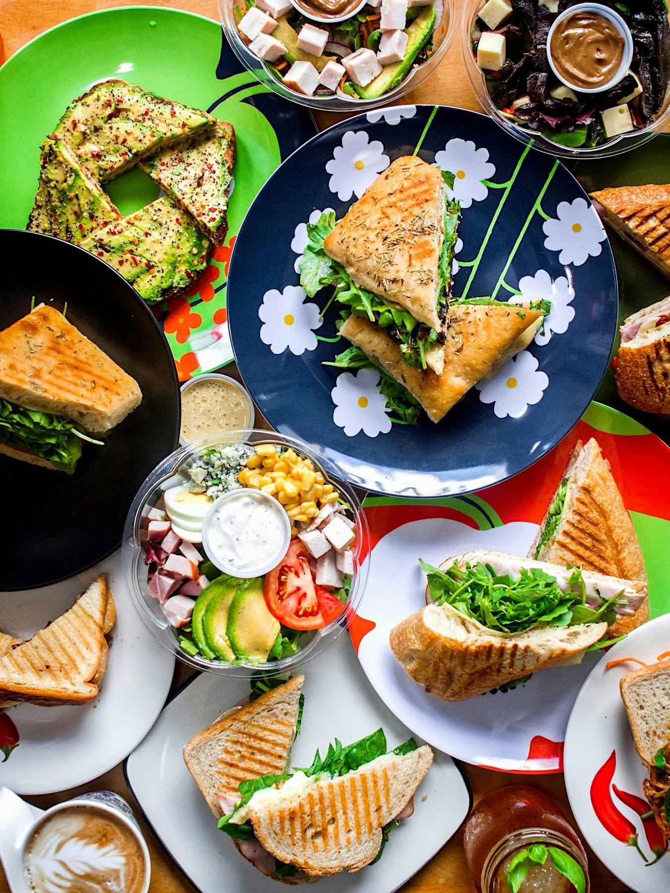 plates of food on a table, most of them sandwiches