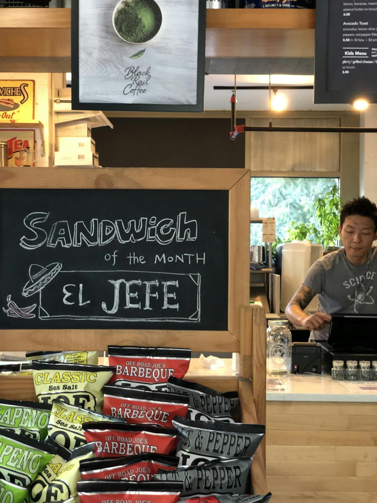 a chalkboard sign with a person setting behind on the background 