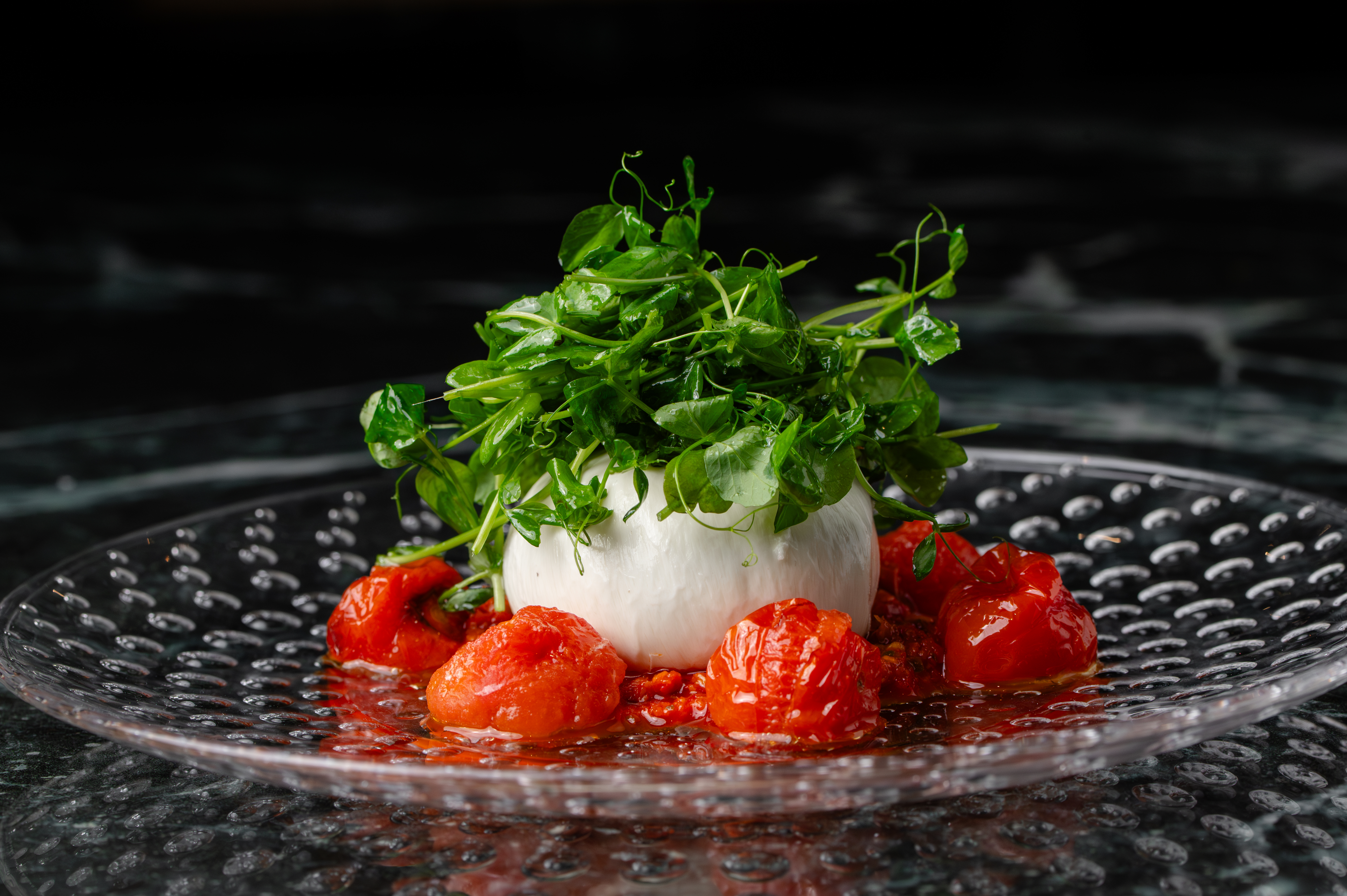 Burrata with roasted tomatoes and greens at Leola Baha Mar — a simple yet stunning Italian appetizer.