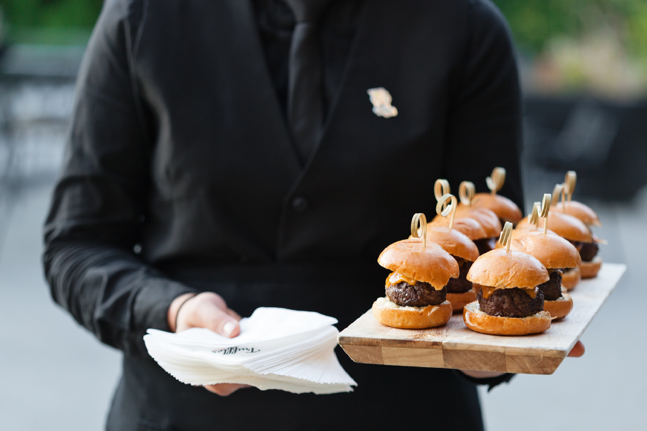 truffles fine foods server holding a platter of burgers