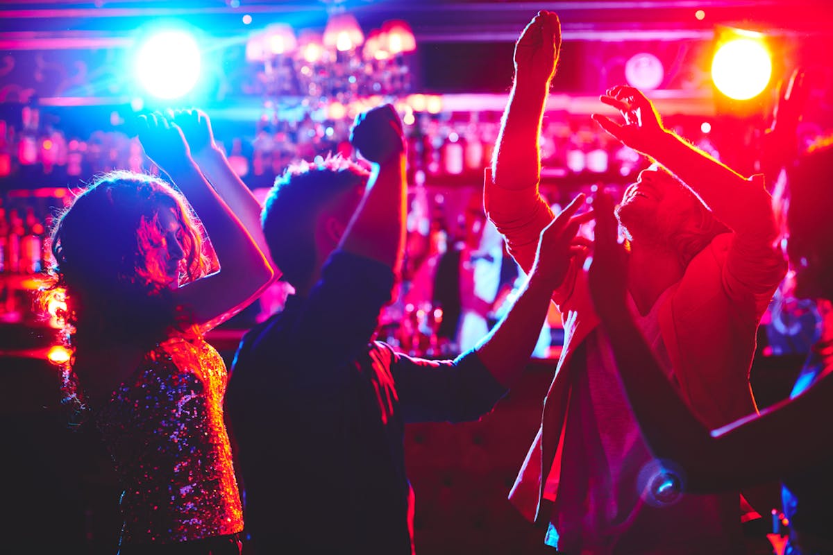 people dancing at a bar with pink and purple lights