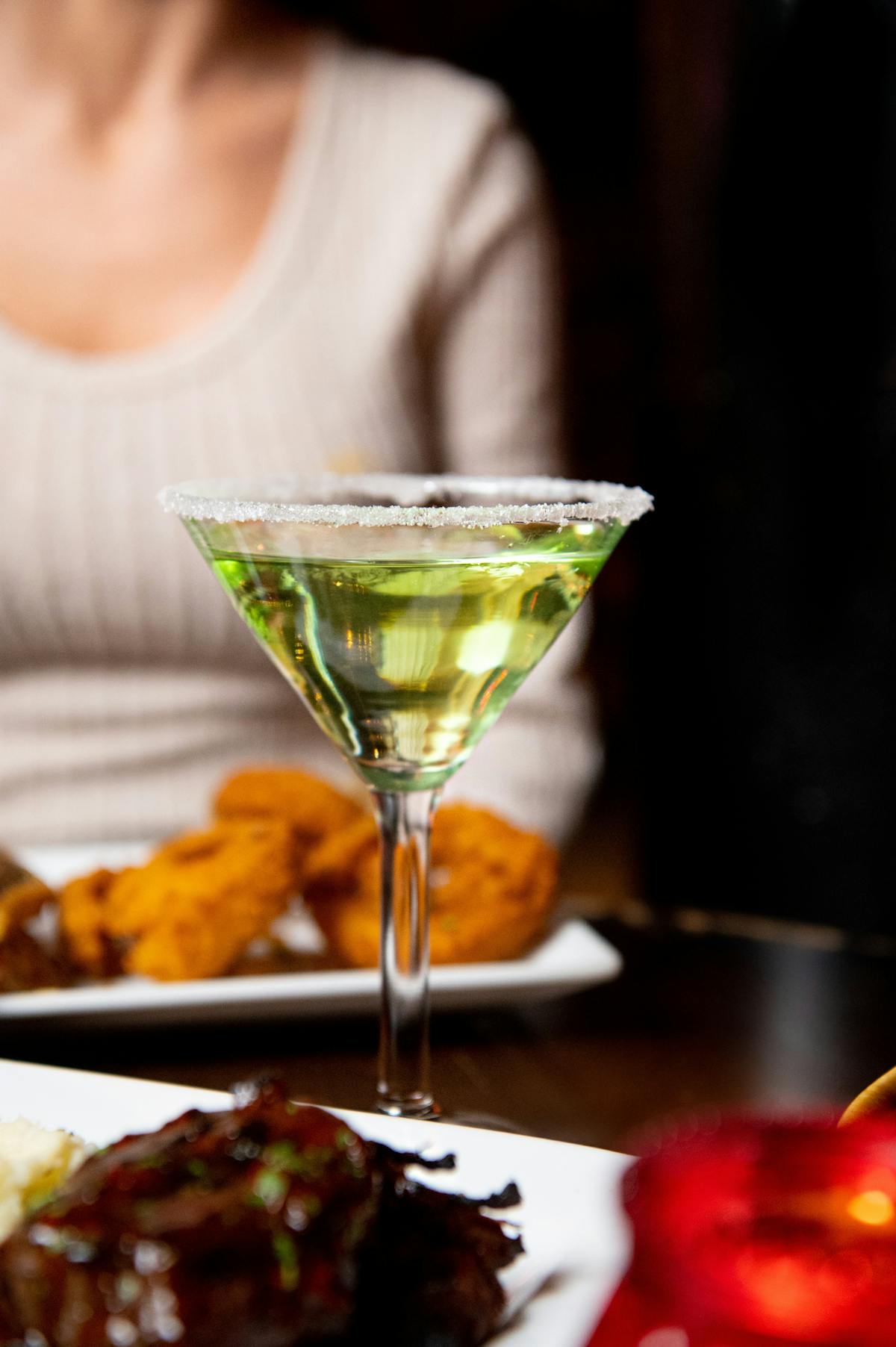 a close up of a person sitting at a table with food and drinks