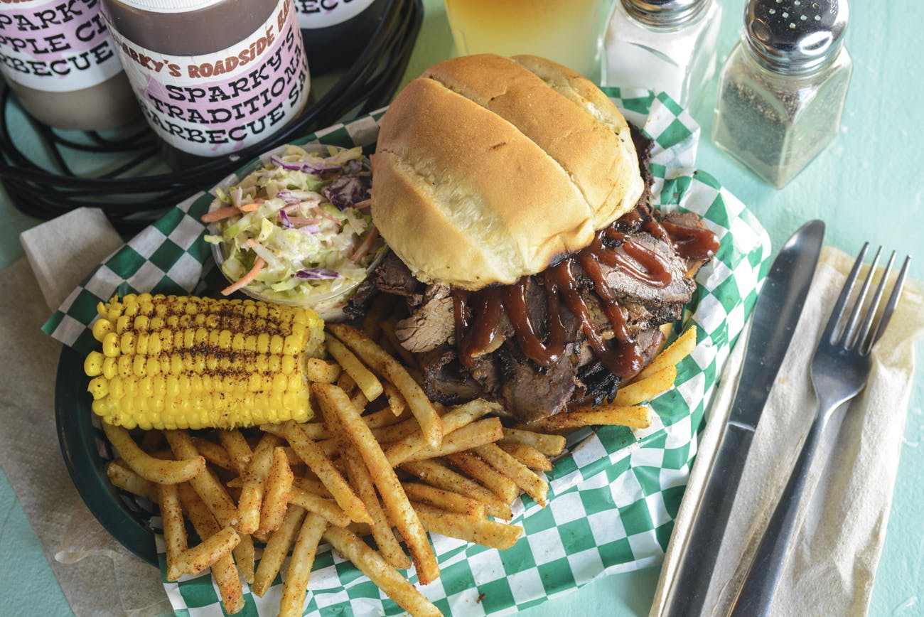 a sandwich, coleslaw, fries and corn on a plate