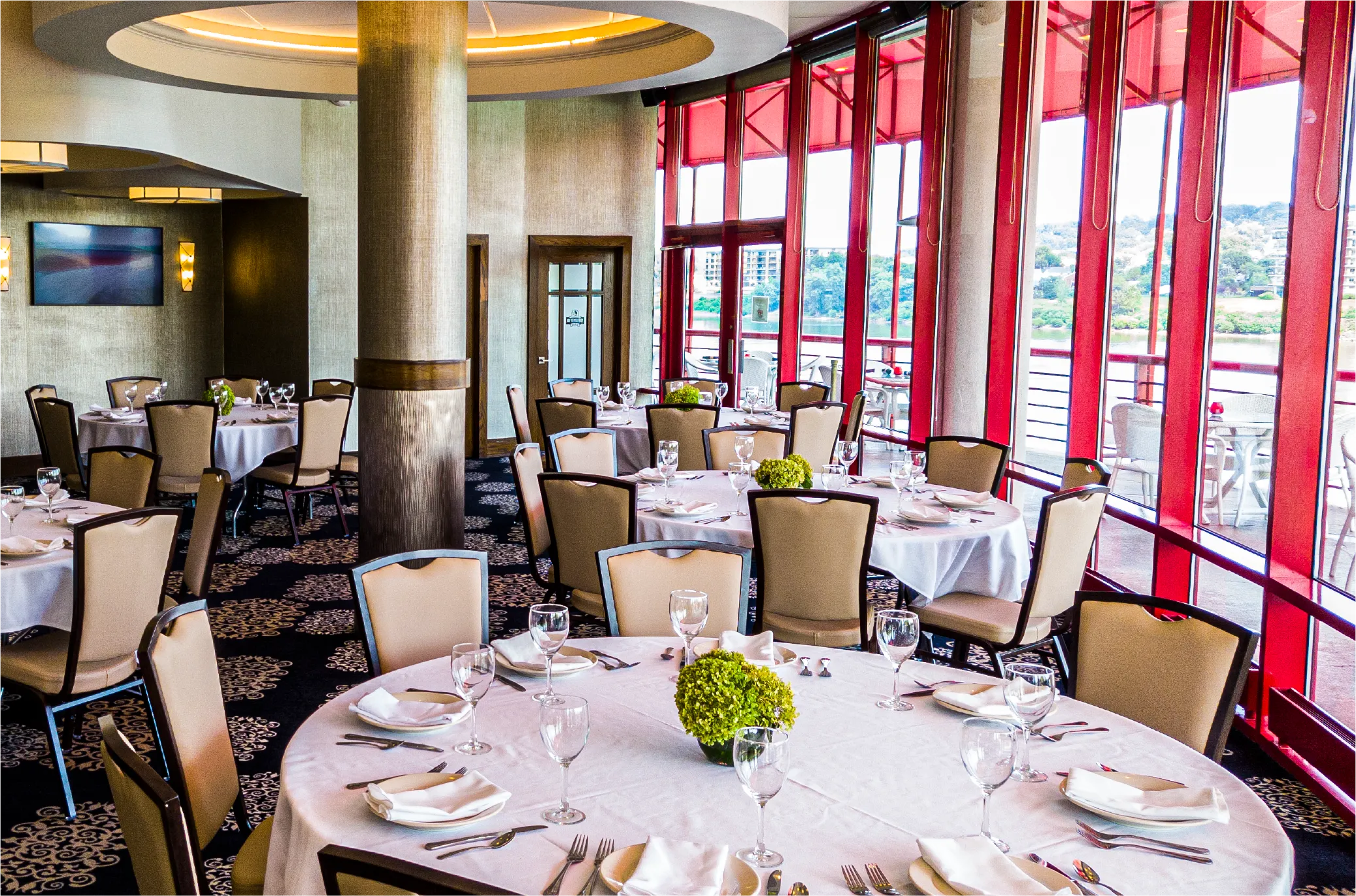 Private dining room with red-framed windows overlooking the river
