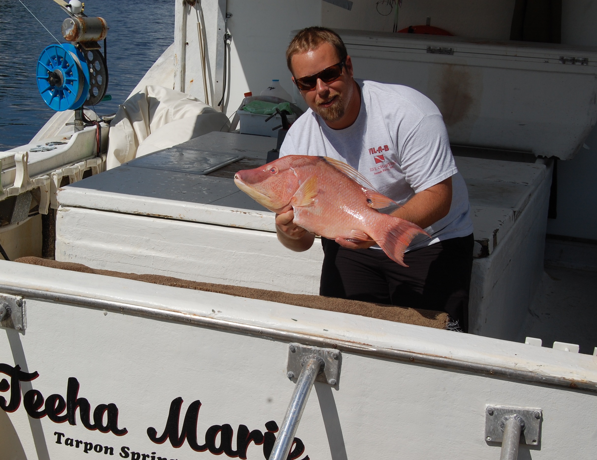 a man on a boat holding a big fish