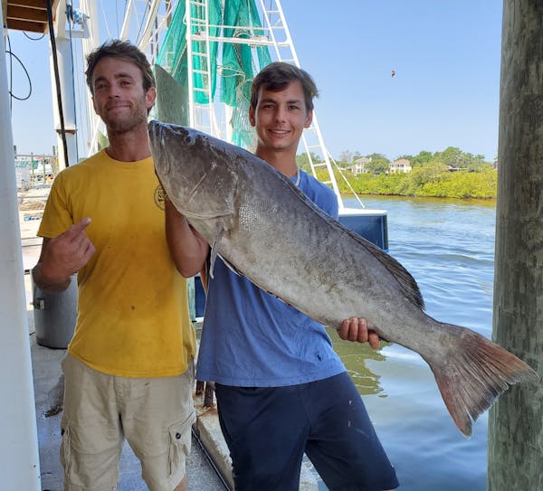 two young men holding a big fish