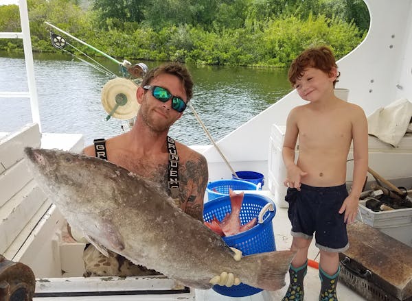 a man  with his child holding a big fish