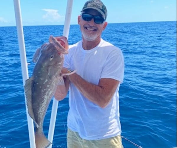 a man holding a fish on a boat in a body of water