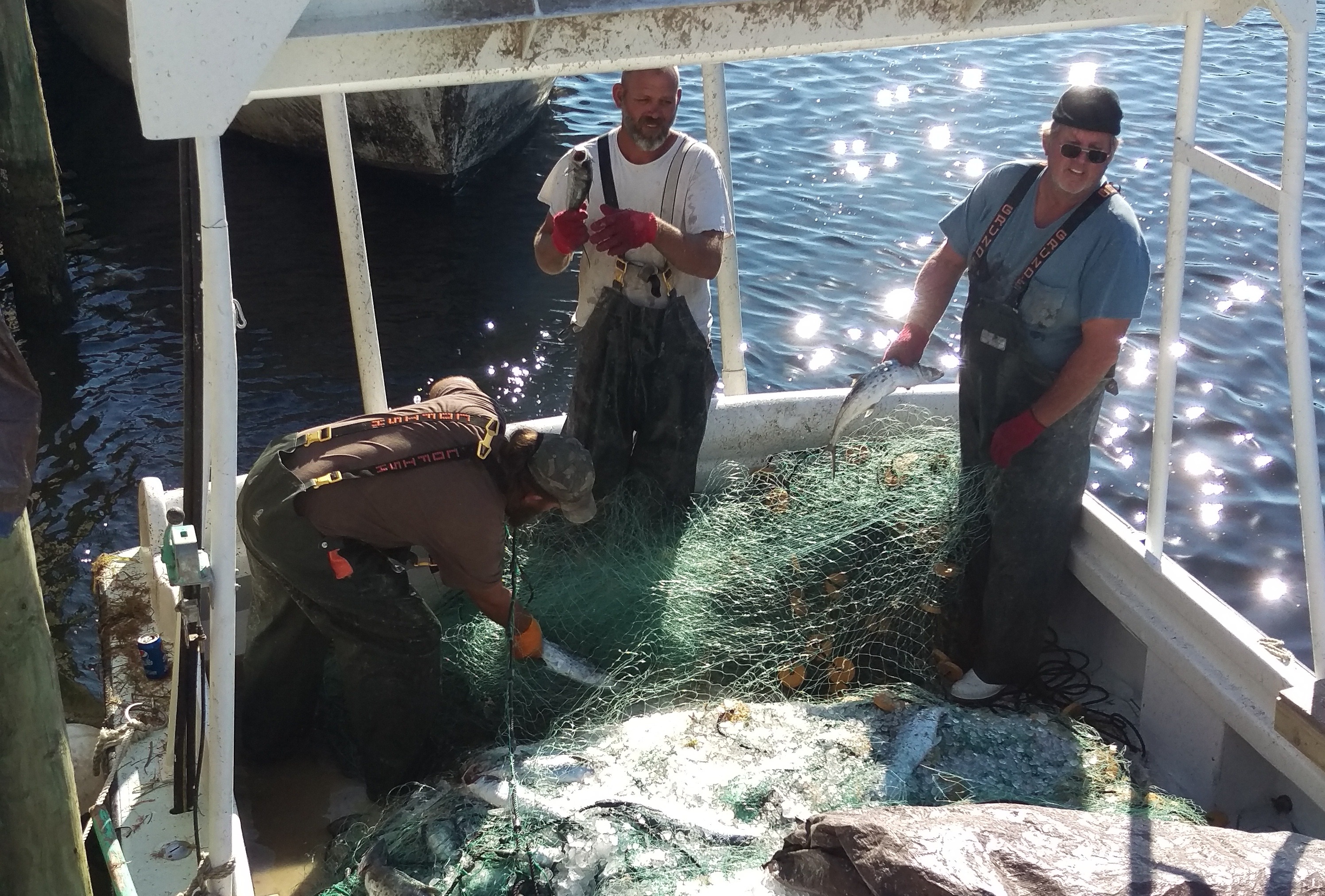 a group of men on a boat fishing on the lake