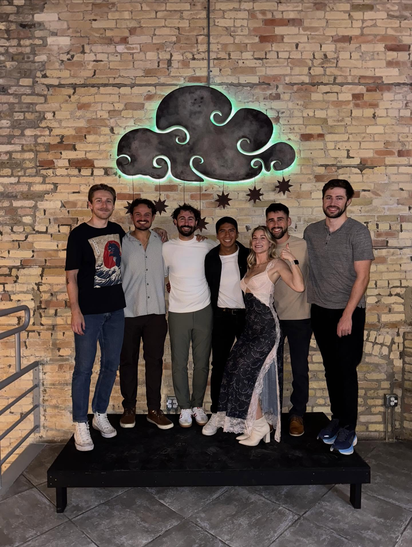 a group of people posing for a photo in front of a brick wall