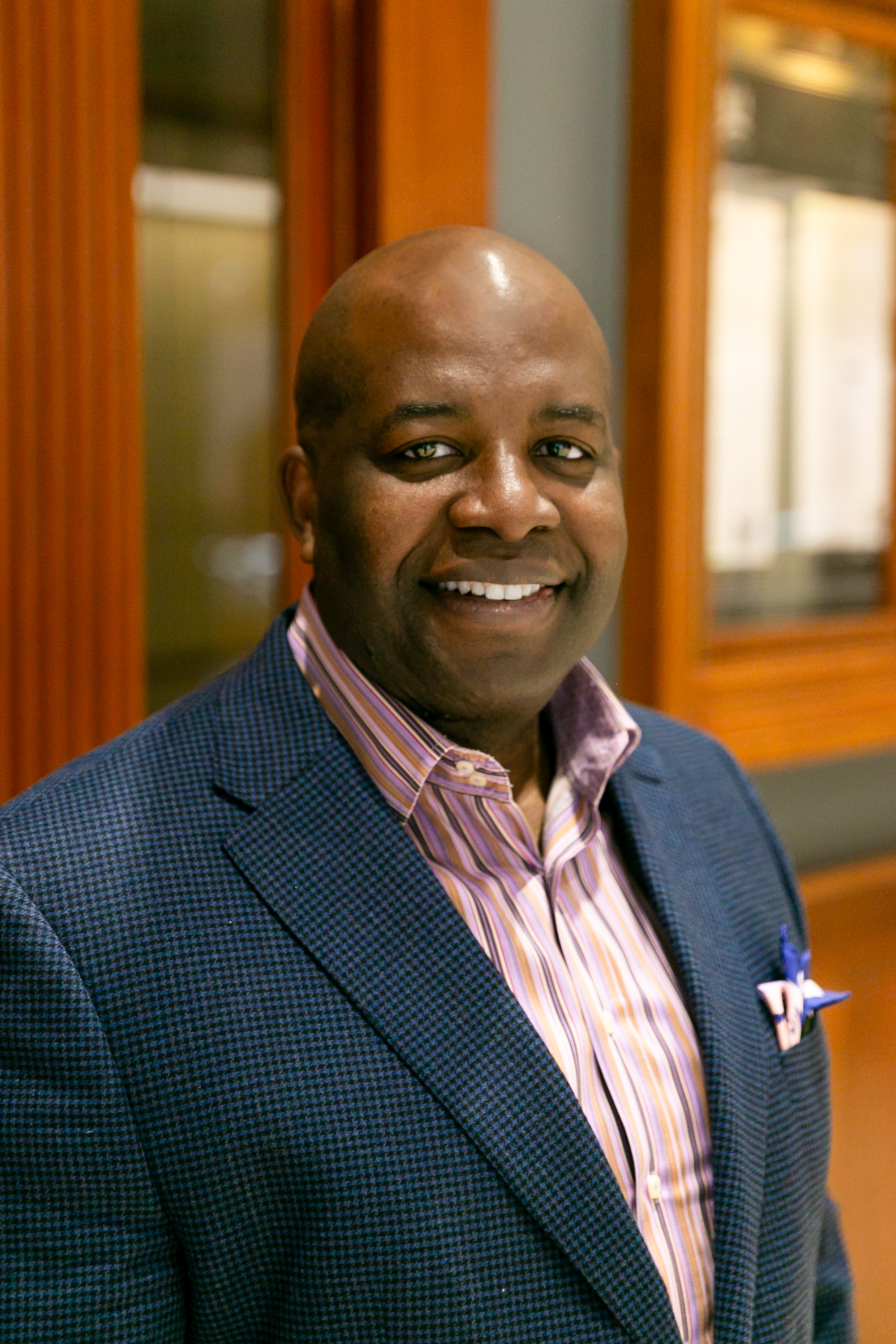 a man wearing a suit and tie smiling at the camera