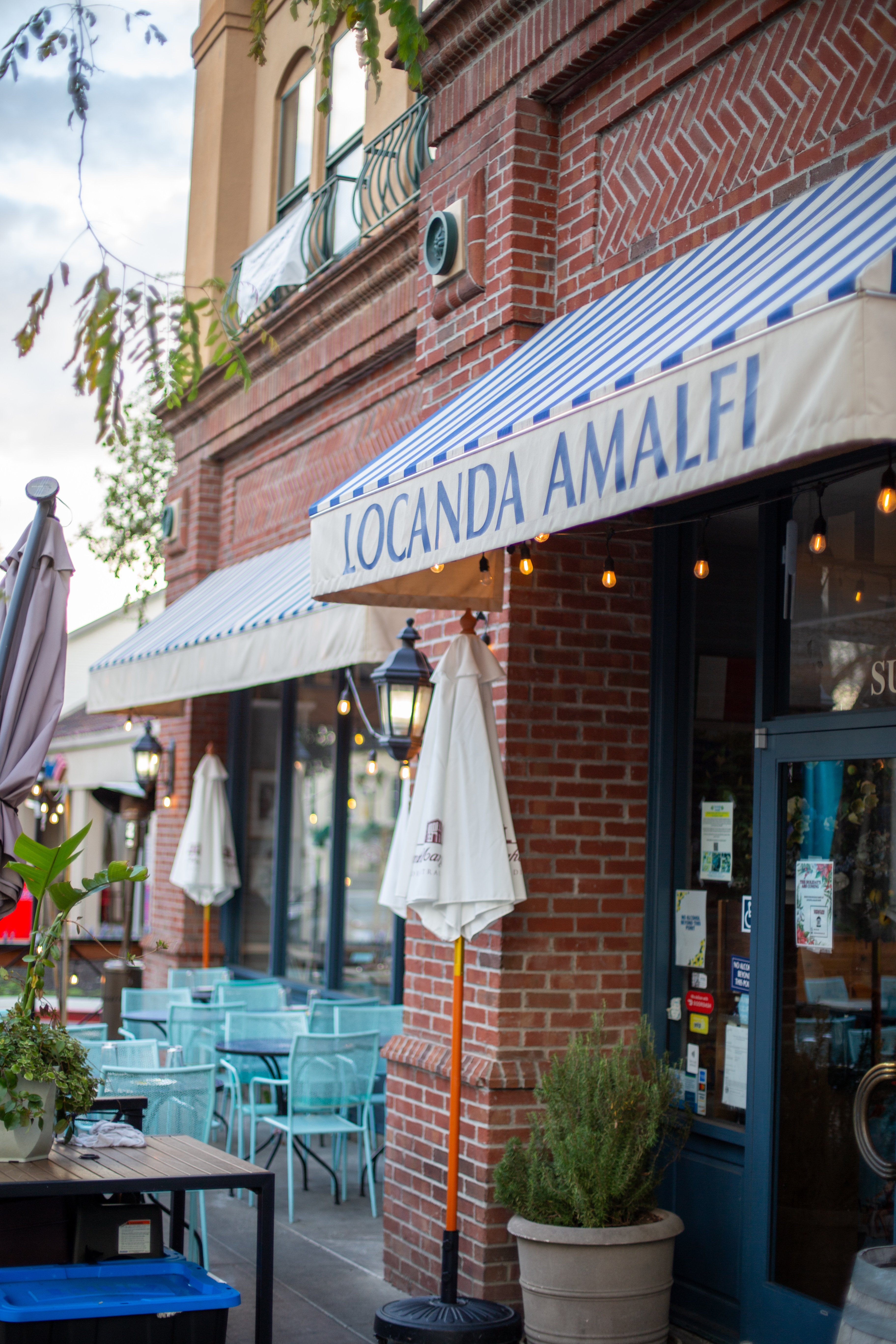 a building with a brick wall and a blue and white striped awning