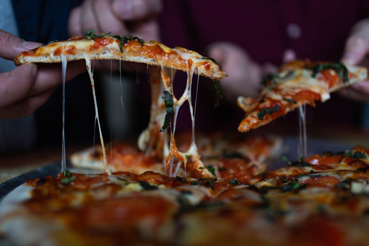 a hand holding a slice of pizza