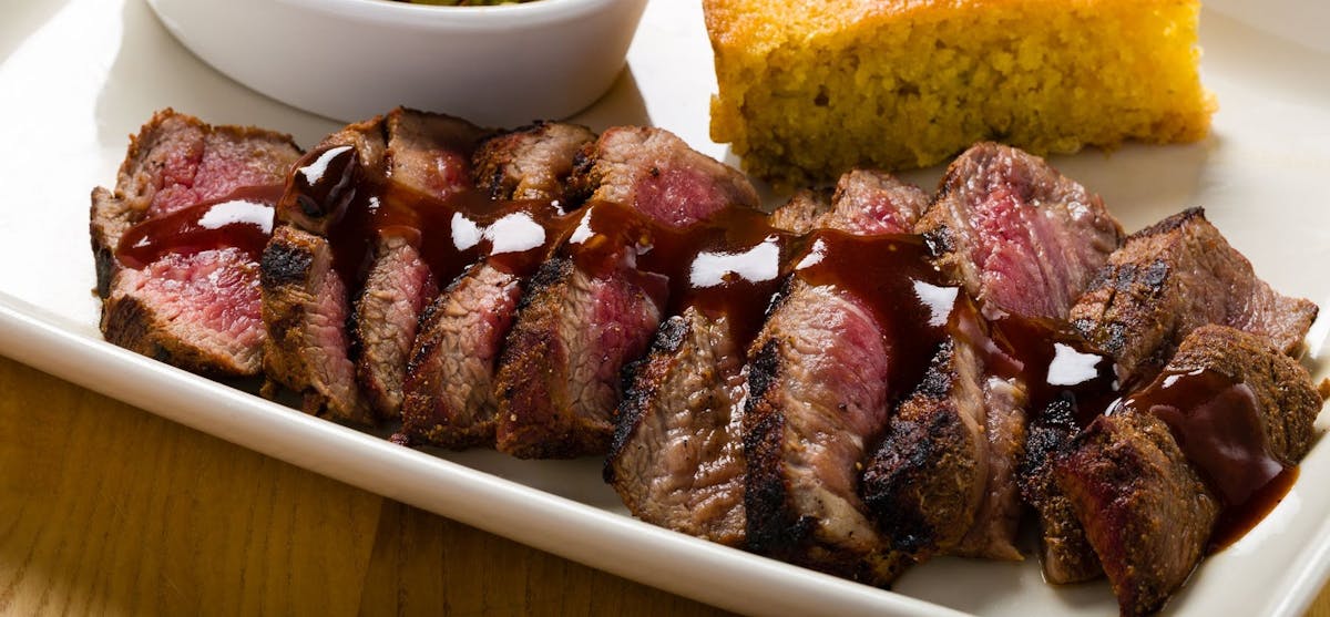 steak slices with barbecue sauce, corn bread and coleslaw
