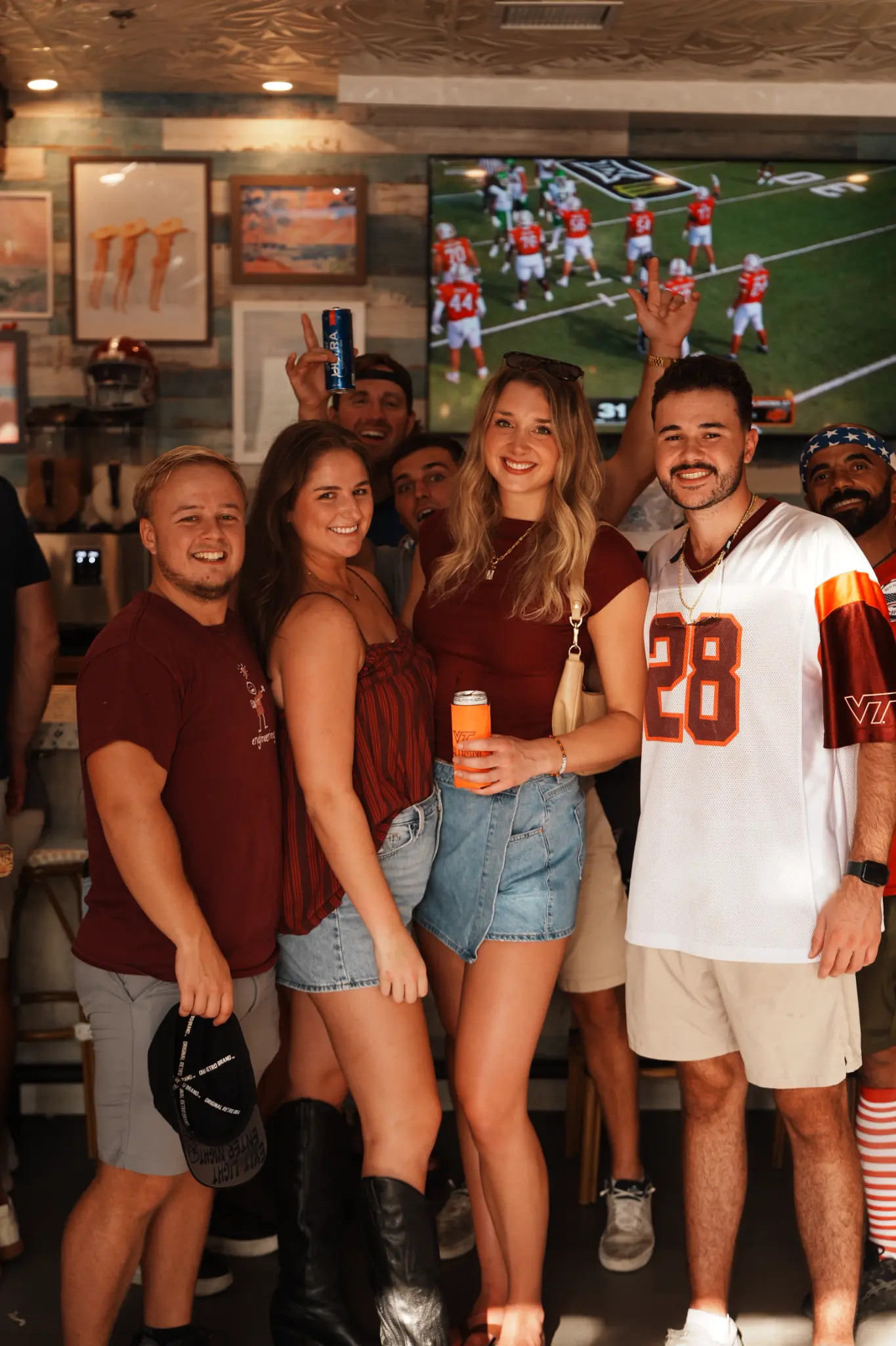 A group of football fans posing in front of a television inside Share House