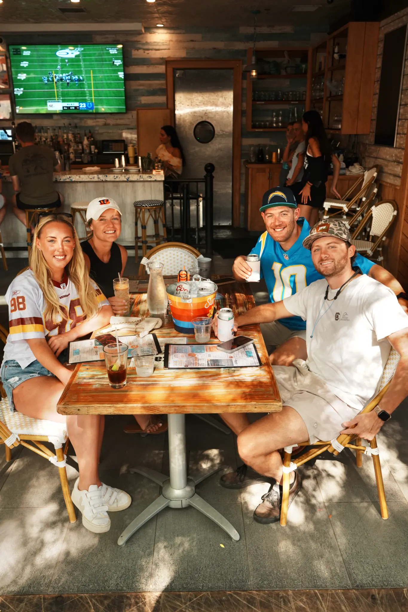 Friends in football jerseys gathered around a table inside Share House