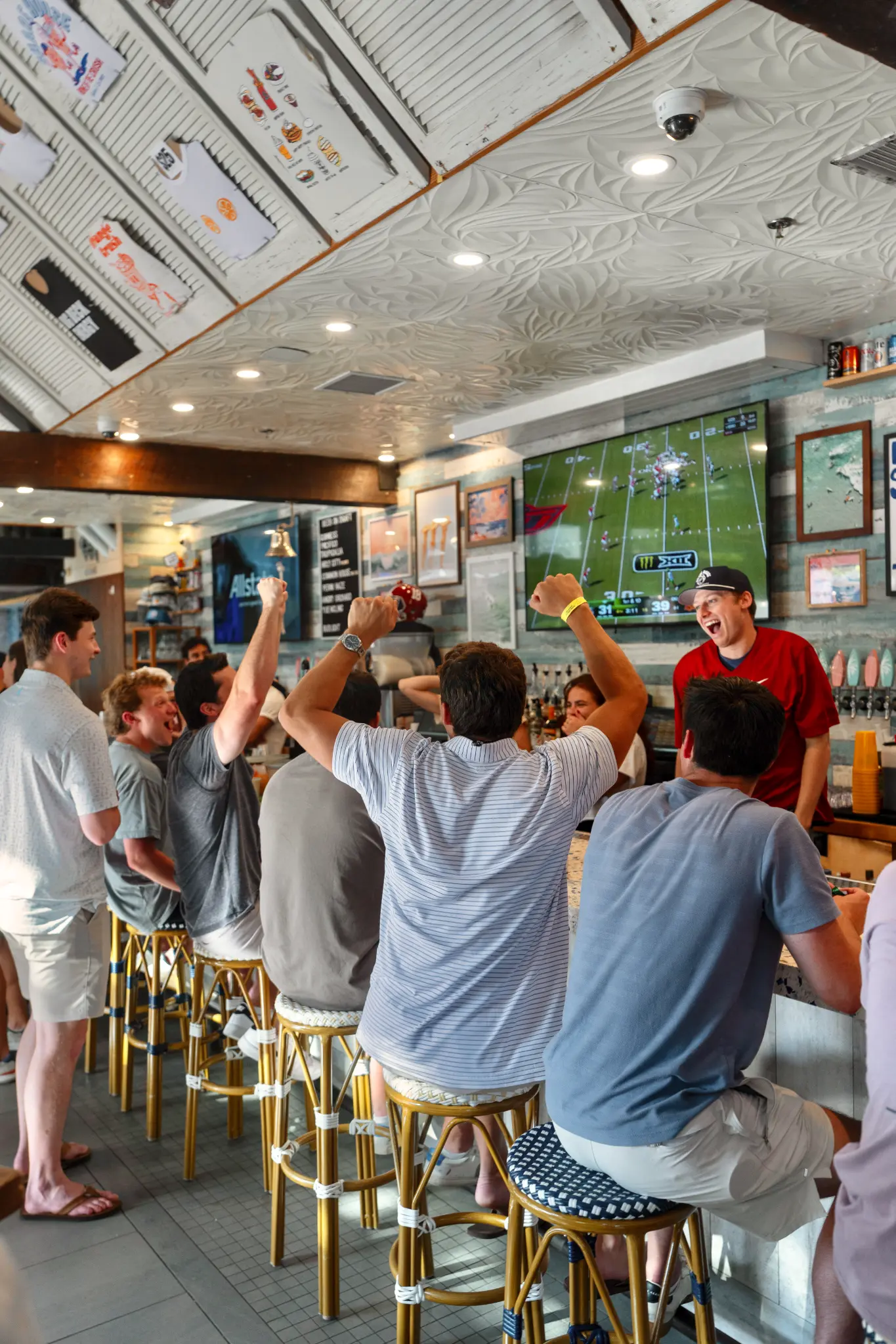 Friends cheering while football plays on a television inside Share House