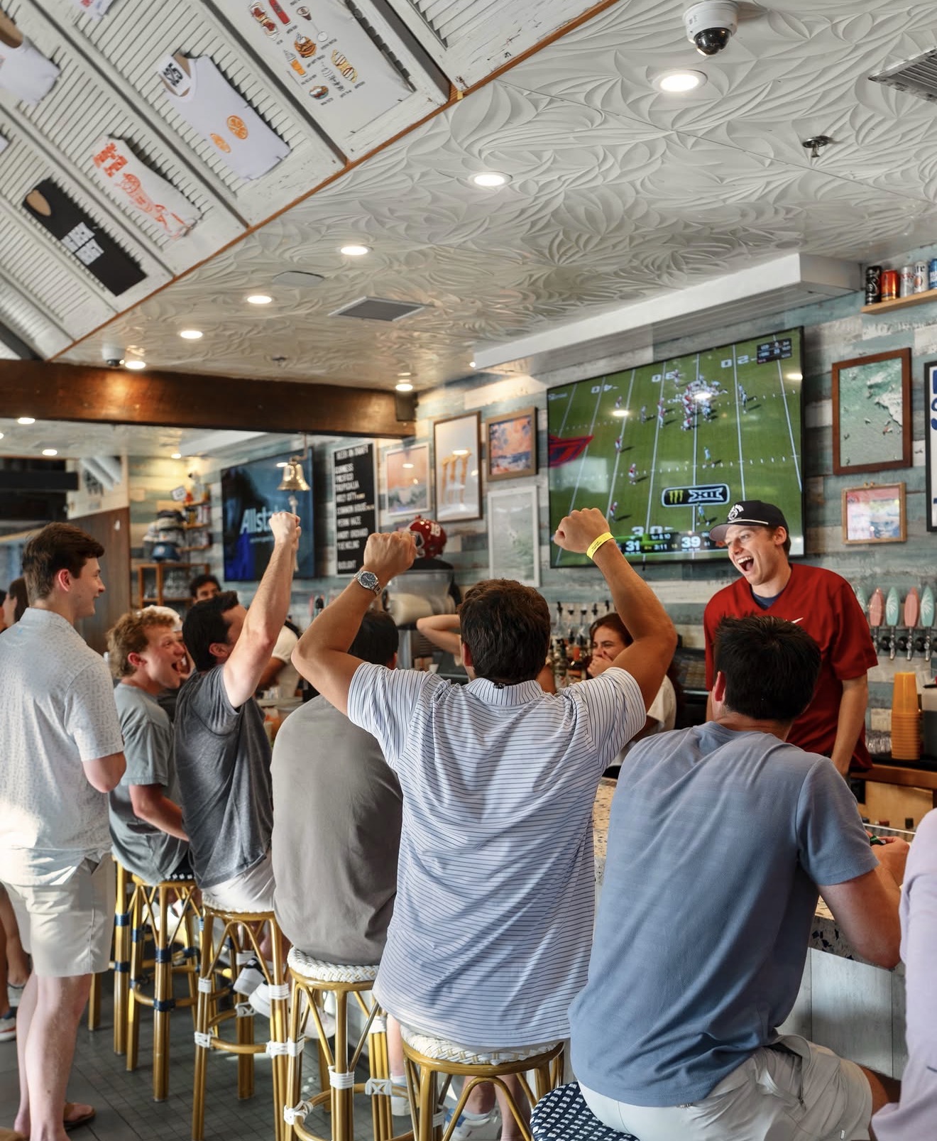 Guests cheering while watching football on the televisions inside Share House