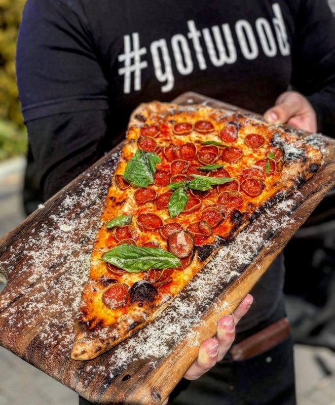 a man holding a slice of pizza