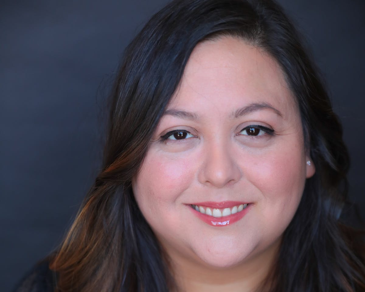 a close up of a woman who is smiling and looking at the camera