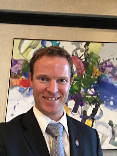 a man wearing a suit and tie smiling at the camera