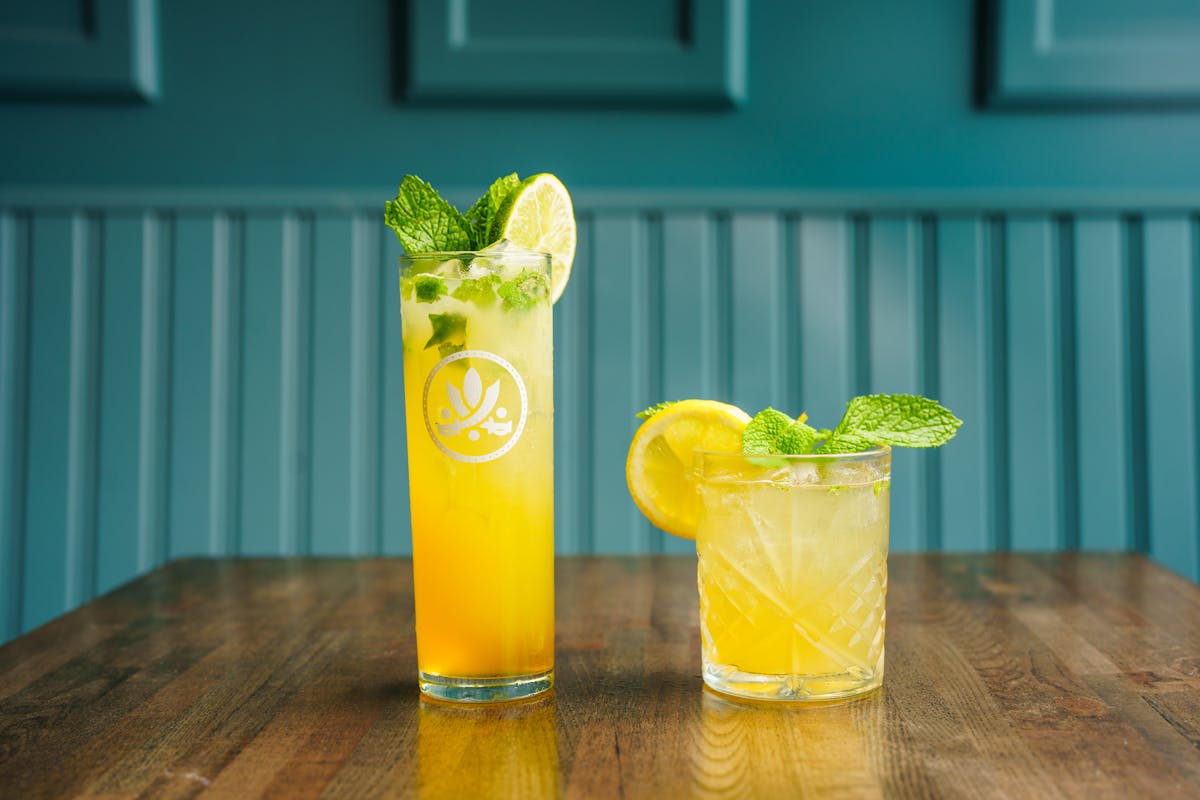 a glass of orange juice next to a vase on a table