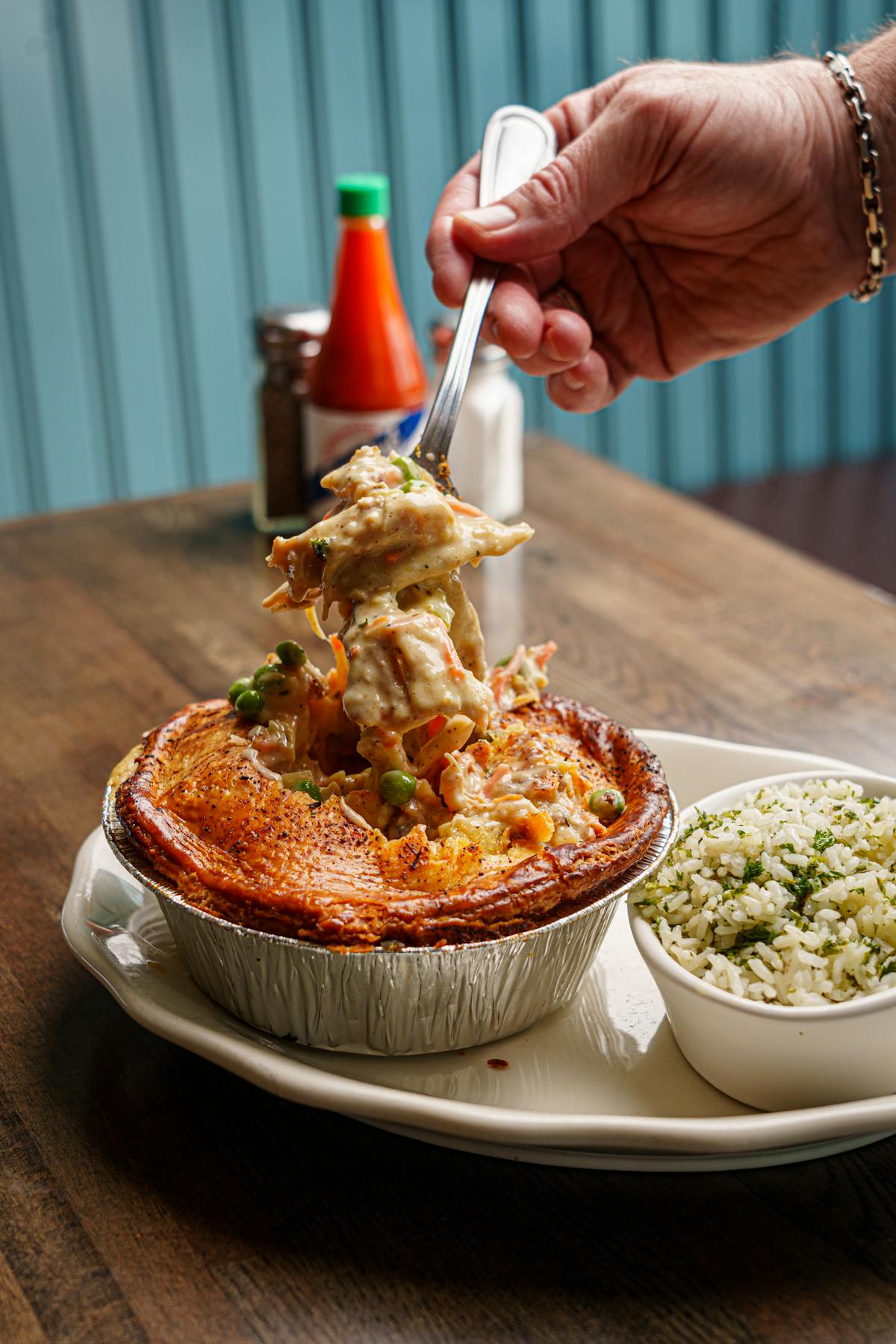 a person holding a plate of food on a table