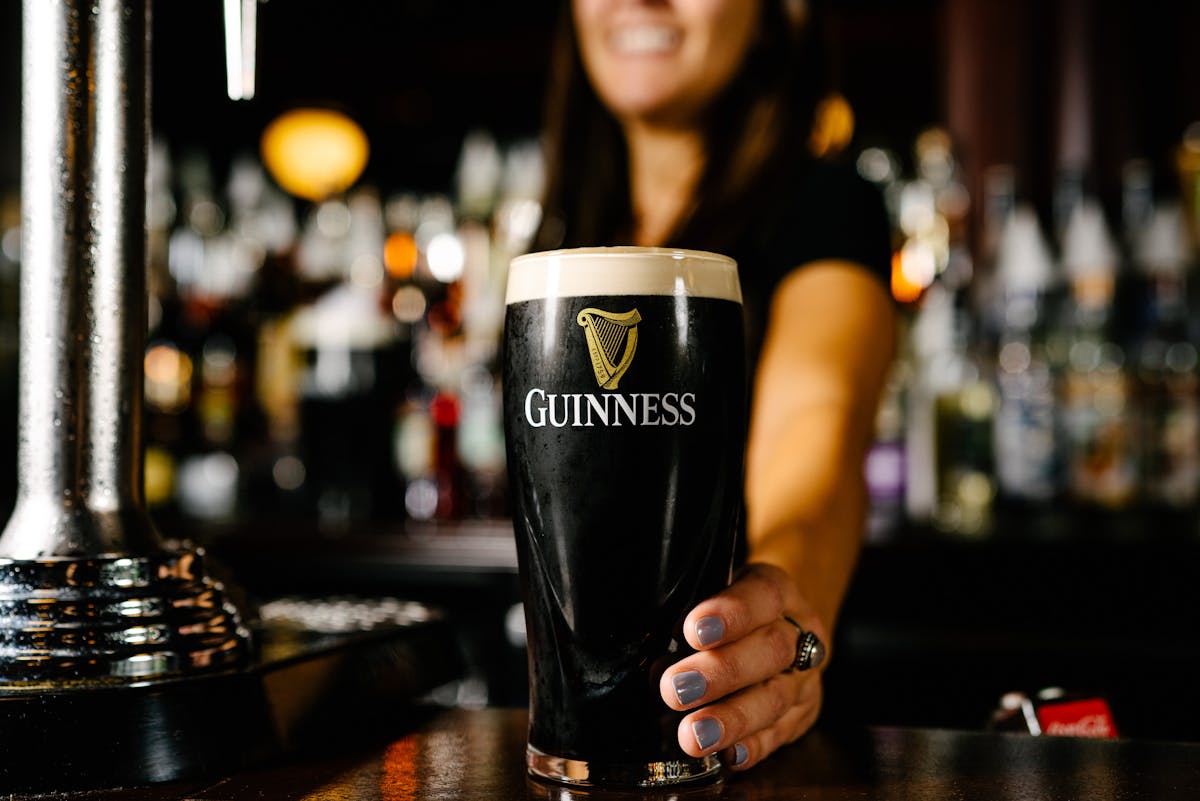 a close up of a person holding a glass of beer on a table