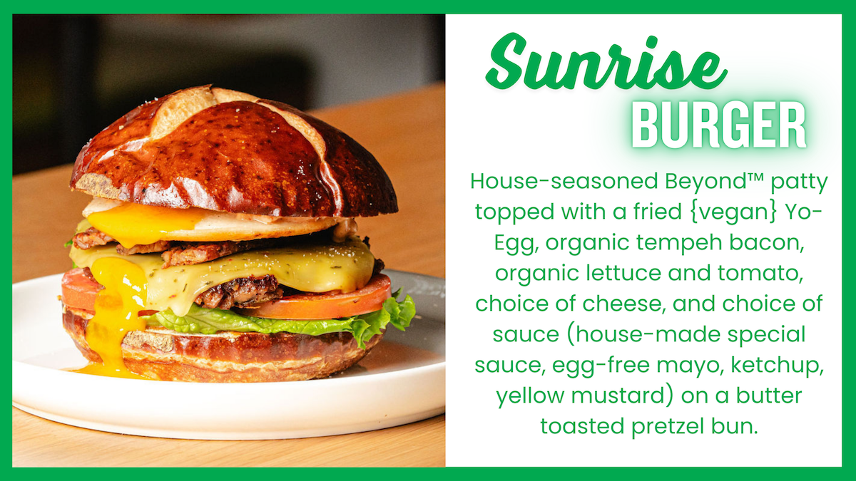 A close-up of the Sunrise Burger on a plate, featuring a house-seasoned Beyond™ patty, fried (vegan) Yo-Egg, organic tempeh bacon, organic lettuce and tomato, melted cheese, and choice of sauce, all on a butter-toasted pretzel bun. The right side of the image contains a text box with the burger’s description in green font, framed by a green border, emphasizing its plant-based ingredients.