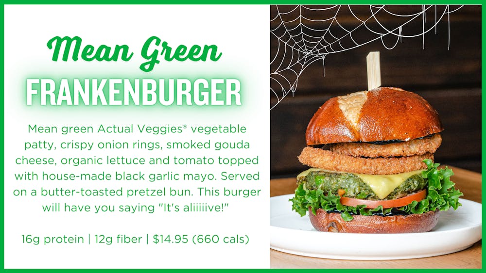 Photo of mean green frankenburger with copy: Mean green Actual Veggies® vegetable patty, crispy onion rings, smoked gouda cheese, organic lettuce and tomato topped with house-made black garlic mayo. Served on a butter-toasted pretzel bun. This burger will have you saying "It's aliiiiive!"   16g protein | 12g fiber | $14.95 (660 cals)
