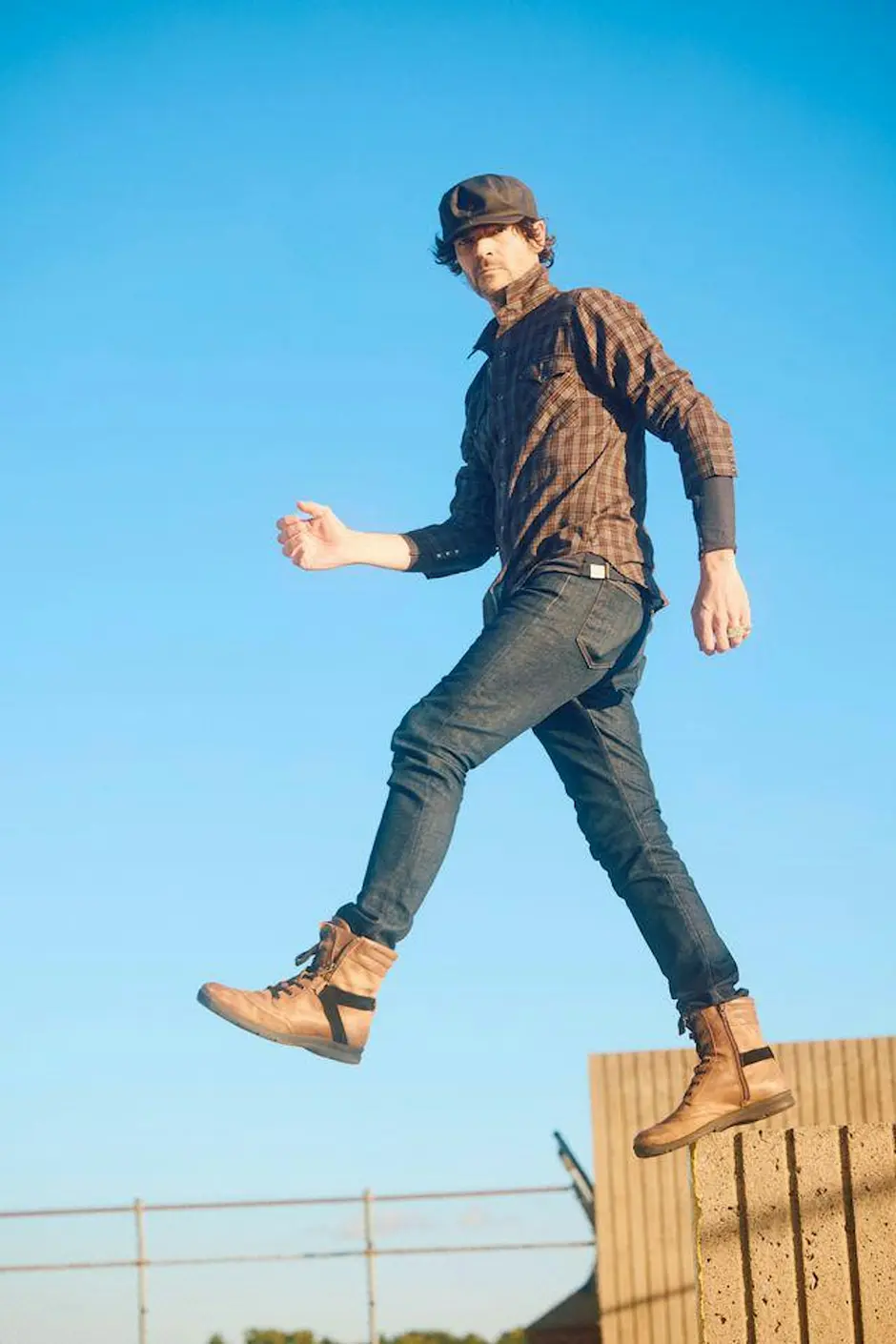 a man in a hat and boots jumping in the air