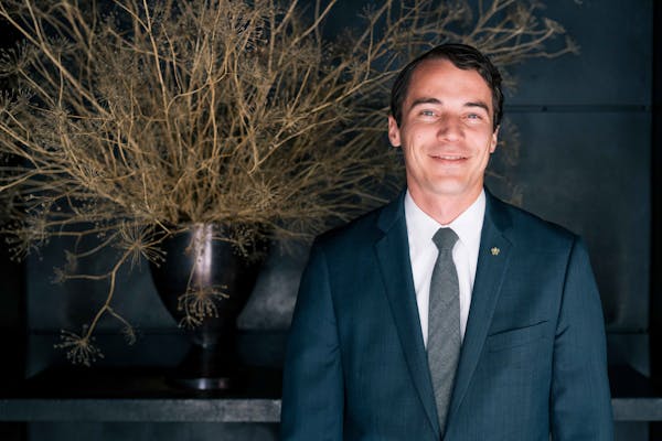 a man wearing a suit and tie smiling at the camera