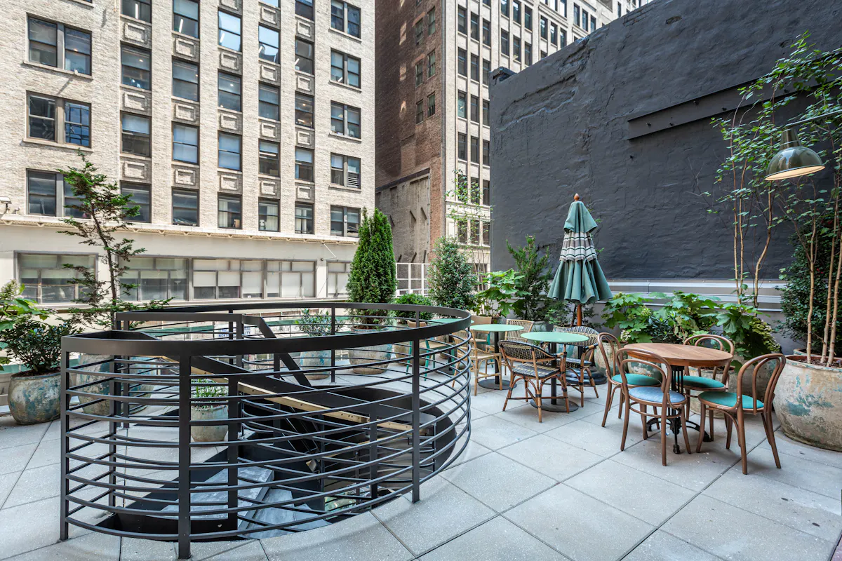 a patio with tables and chairs and a black railing