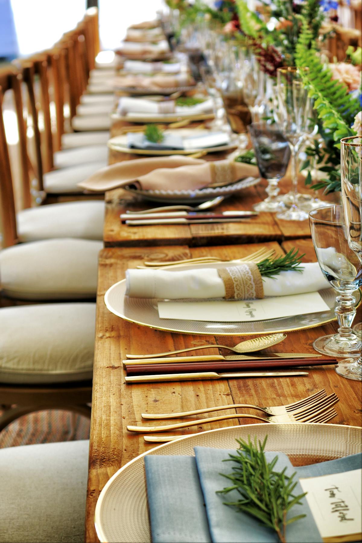a wooden table lined with plates and silverware