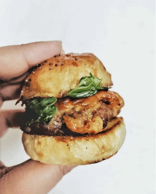  A person holding a beef and cheese slider