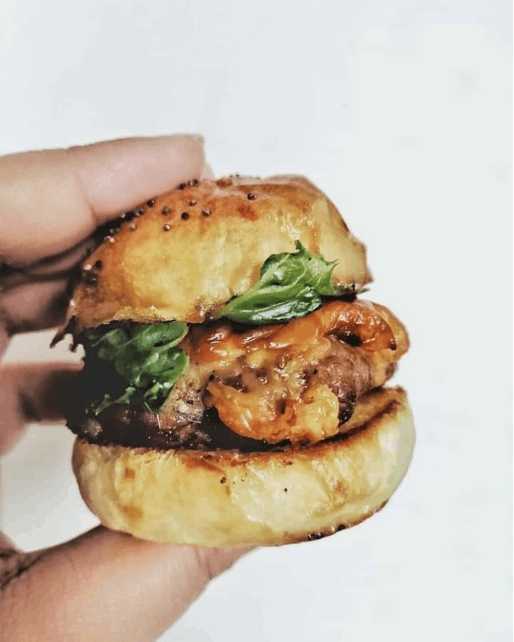 A person holding a beef and cheese slider